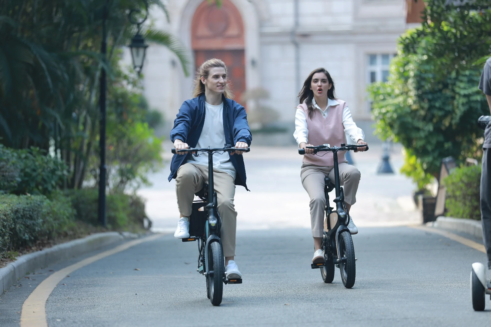 DYU C2 bicicletas elétricas dobráveis com dois ciclistas em uma rua urbana verde