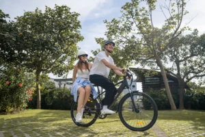 Two city e-bike riders on a green park route wearing cycling helmets