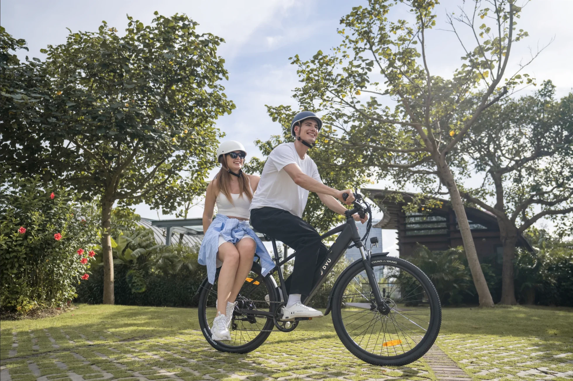 DYU C5 riders on a park path with grass and city surroundings