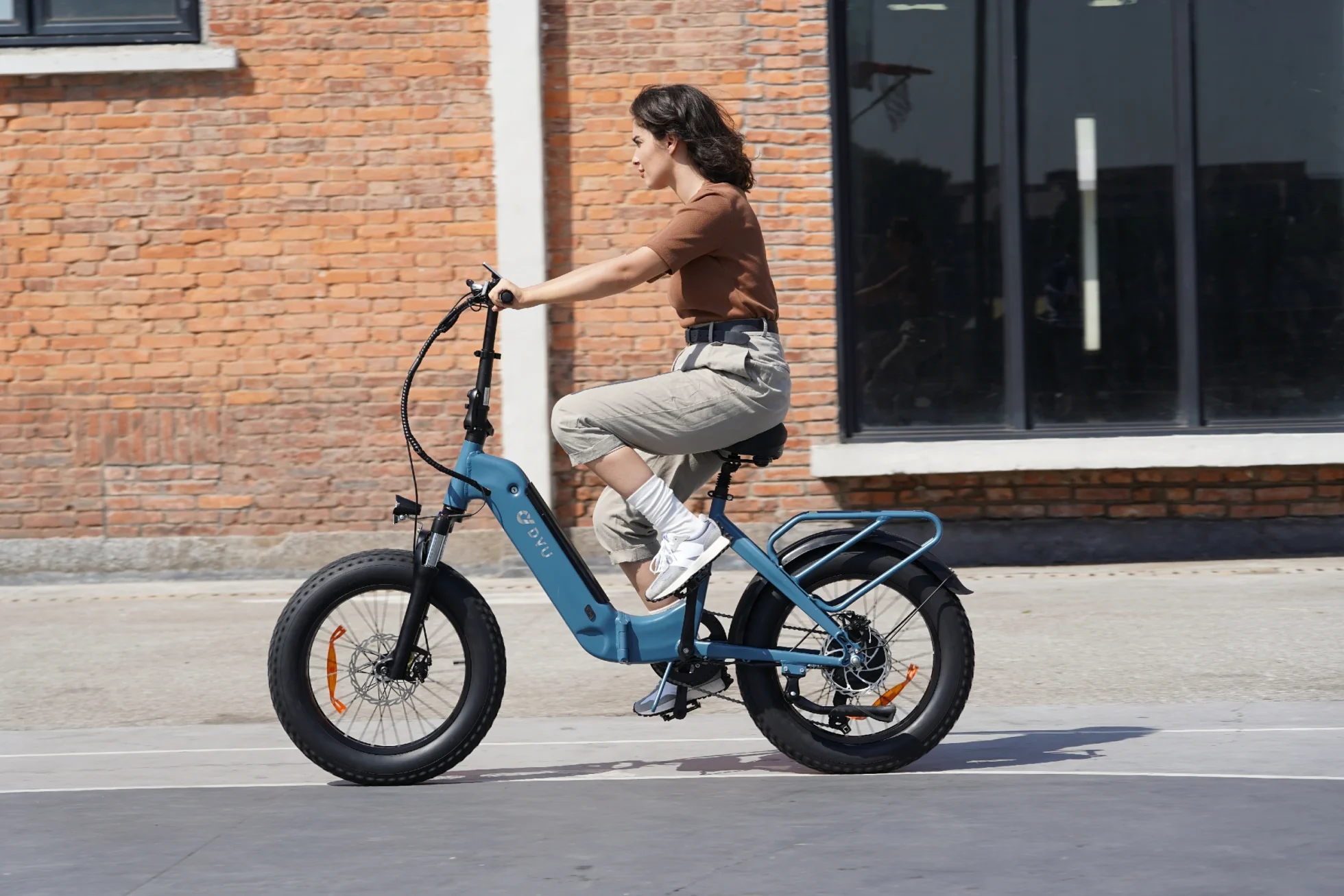 DYU FF500 fat pneu e-bike parada ao lado de um detalhe de parede de tijolos