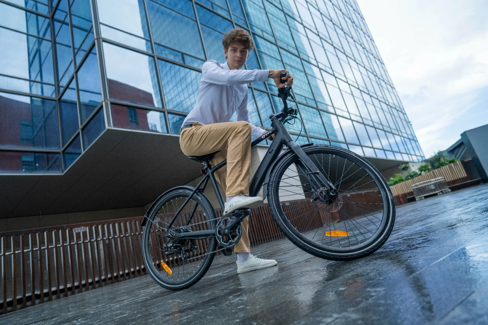 DYU Stroll 1 city e-bike riding near modern architecture during a puncture prevention check
