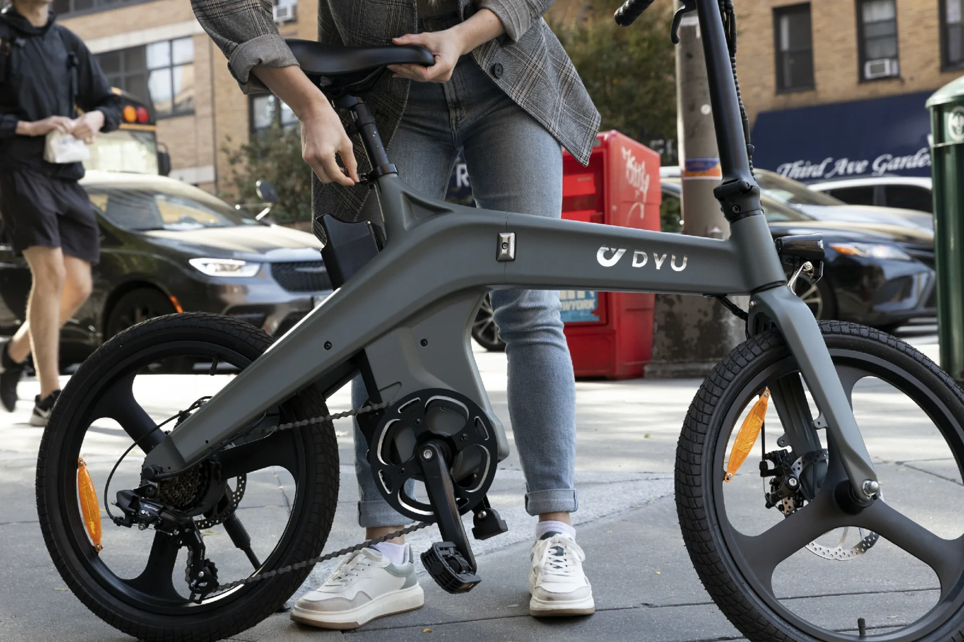 DYU T1 folding e-bike held beside a rider before a portability comparison