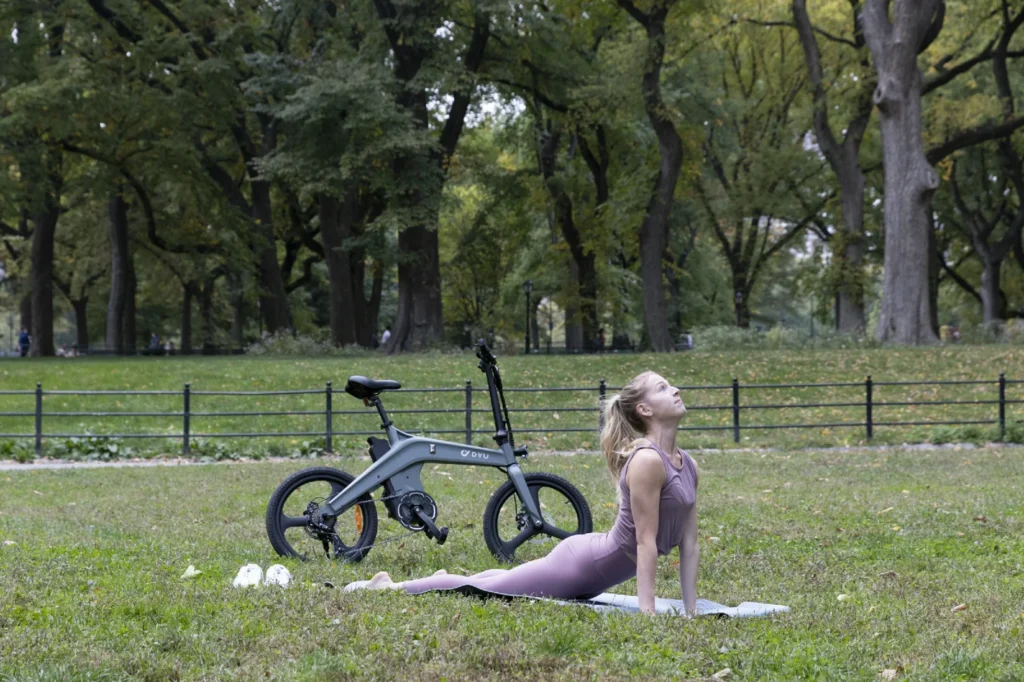 DYU T1 rider stretching beside a foldable e-bike in a park